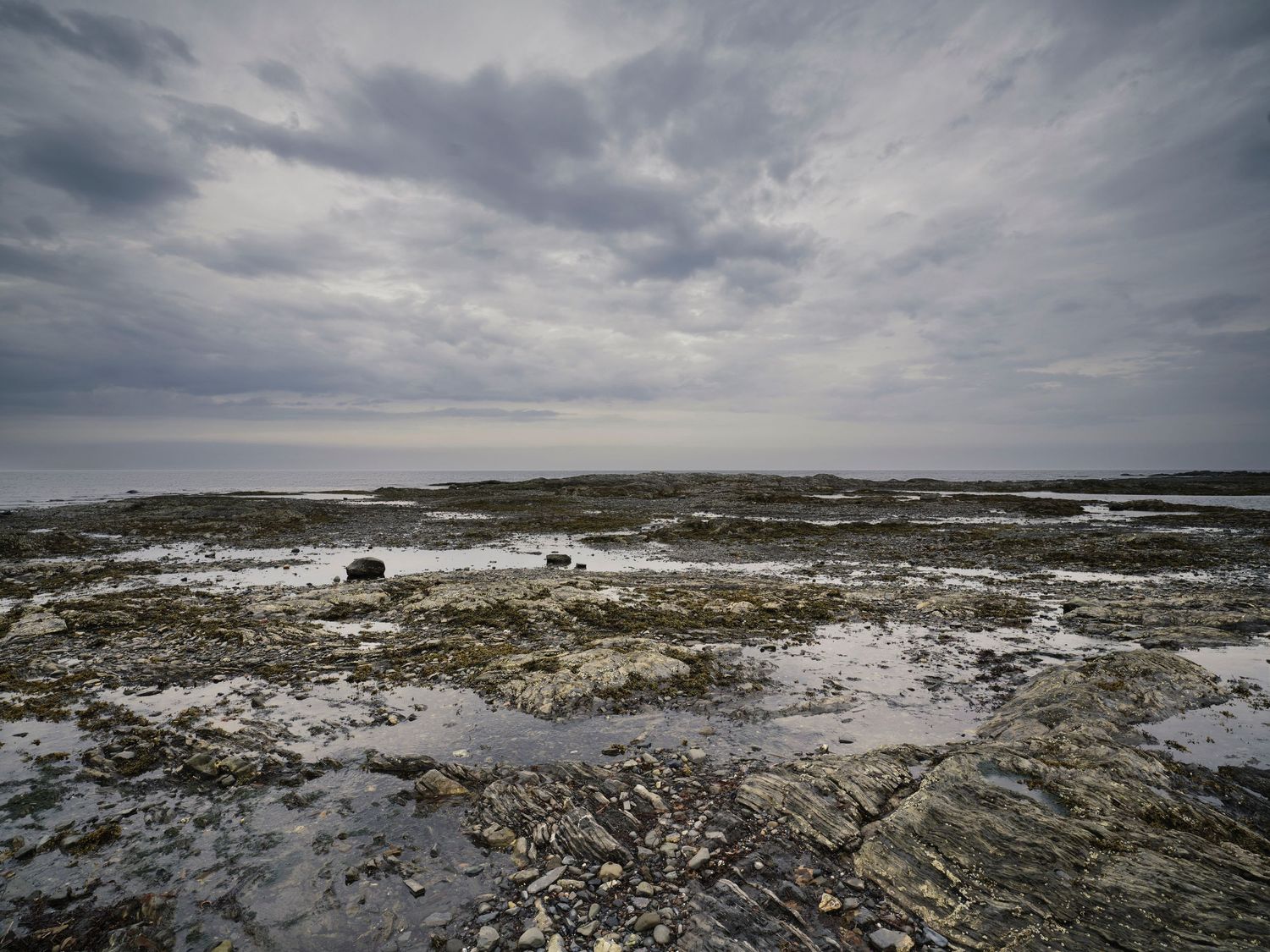 Dramatic cloudy sky over rocky coastal landscape with tidal pools.