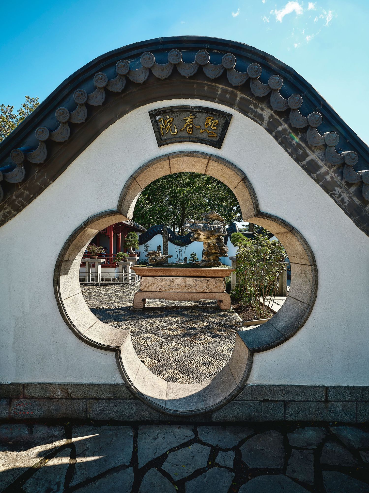 Traditional Chinese garden wall with decorative moon gate windows offering views of the courtyard.
