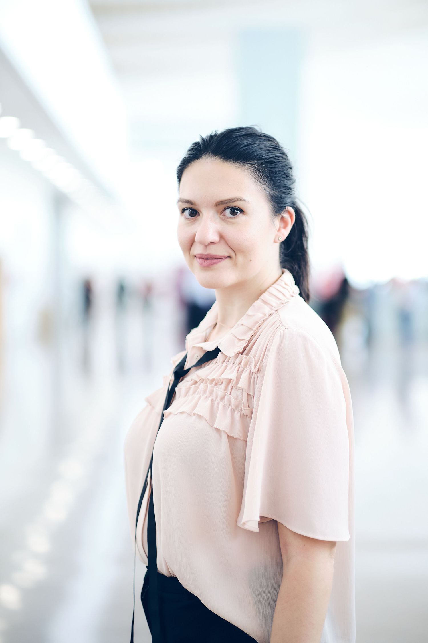 Professional portraits of person wearing pink blouse in bright hallway setting.