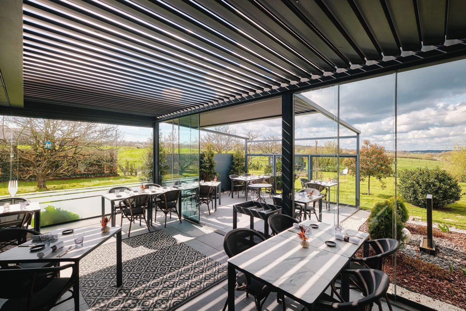 Contemporary outdoor dining space with sleek pergola and expansive views of rolling hills.