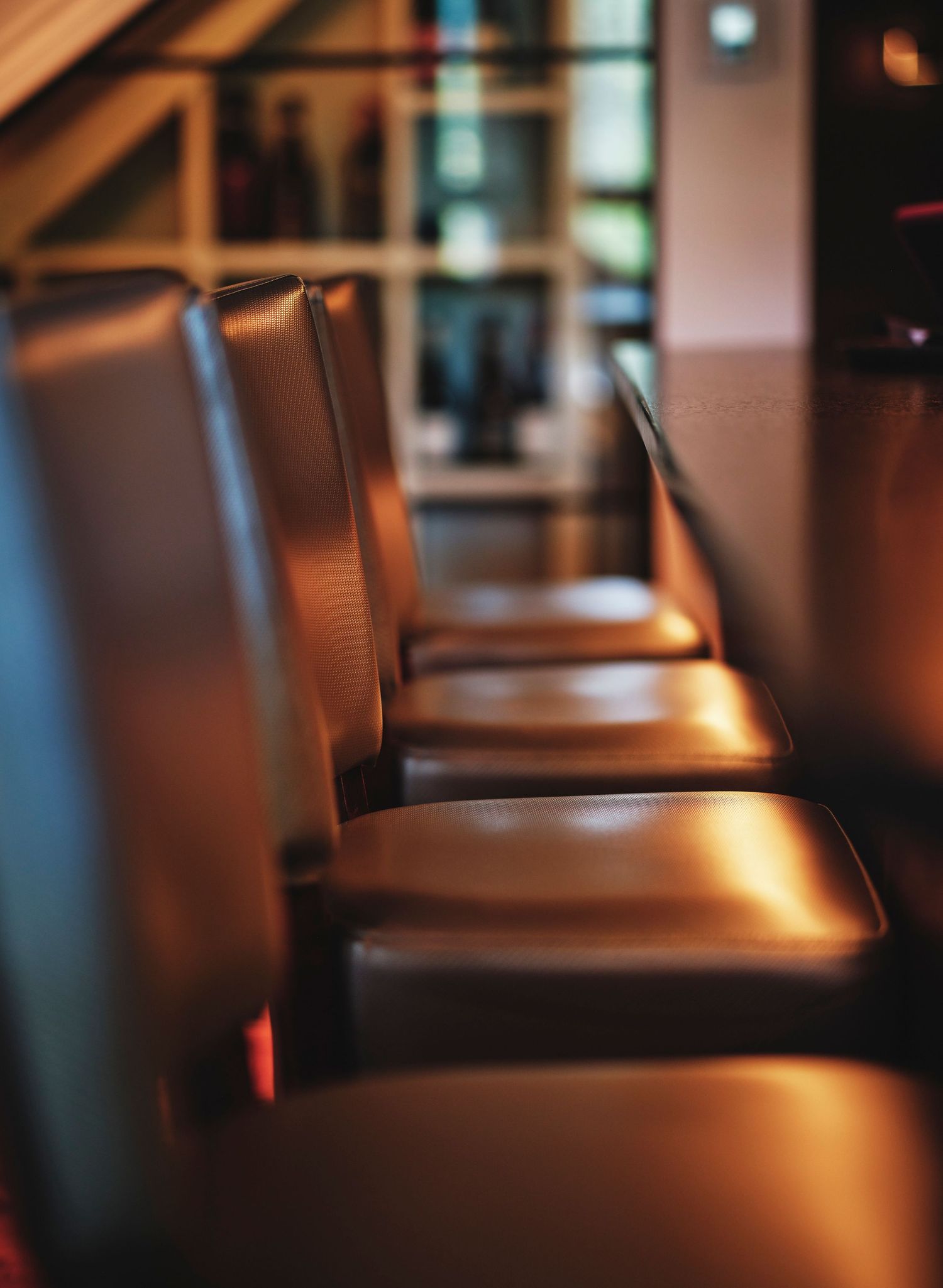 Row of leather dining chairs illuminated by warm spotlighting in a restaurant.