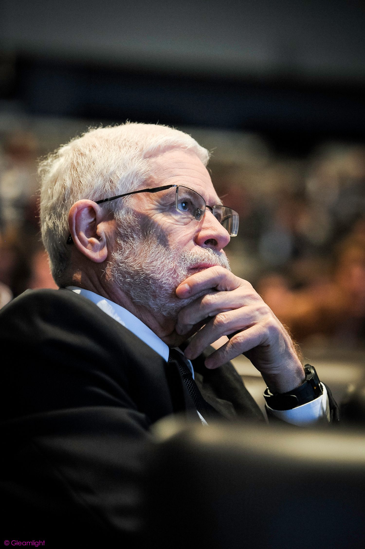 Conference attendee in formal attire listening intently during presentation.