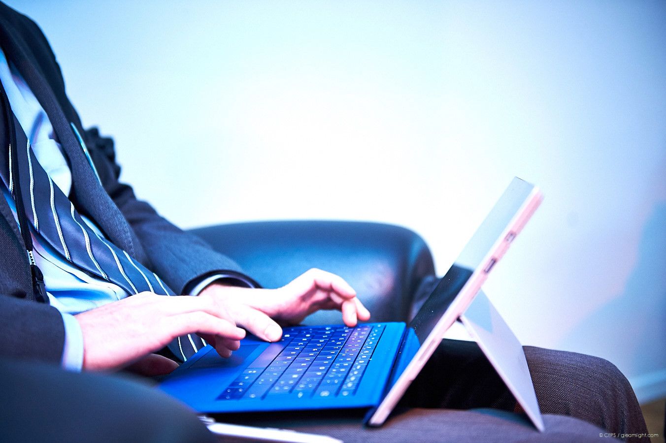 Person typing on a Surface tablet with detachable keyboard in low light conditions.