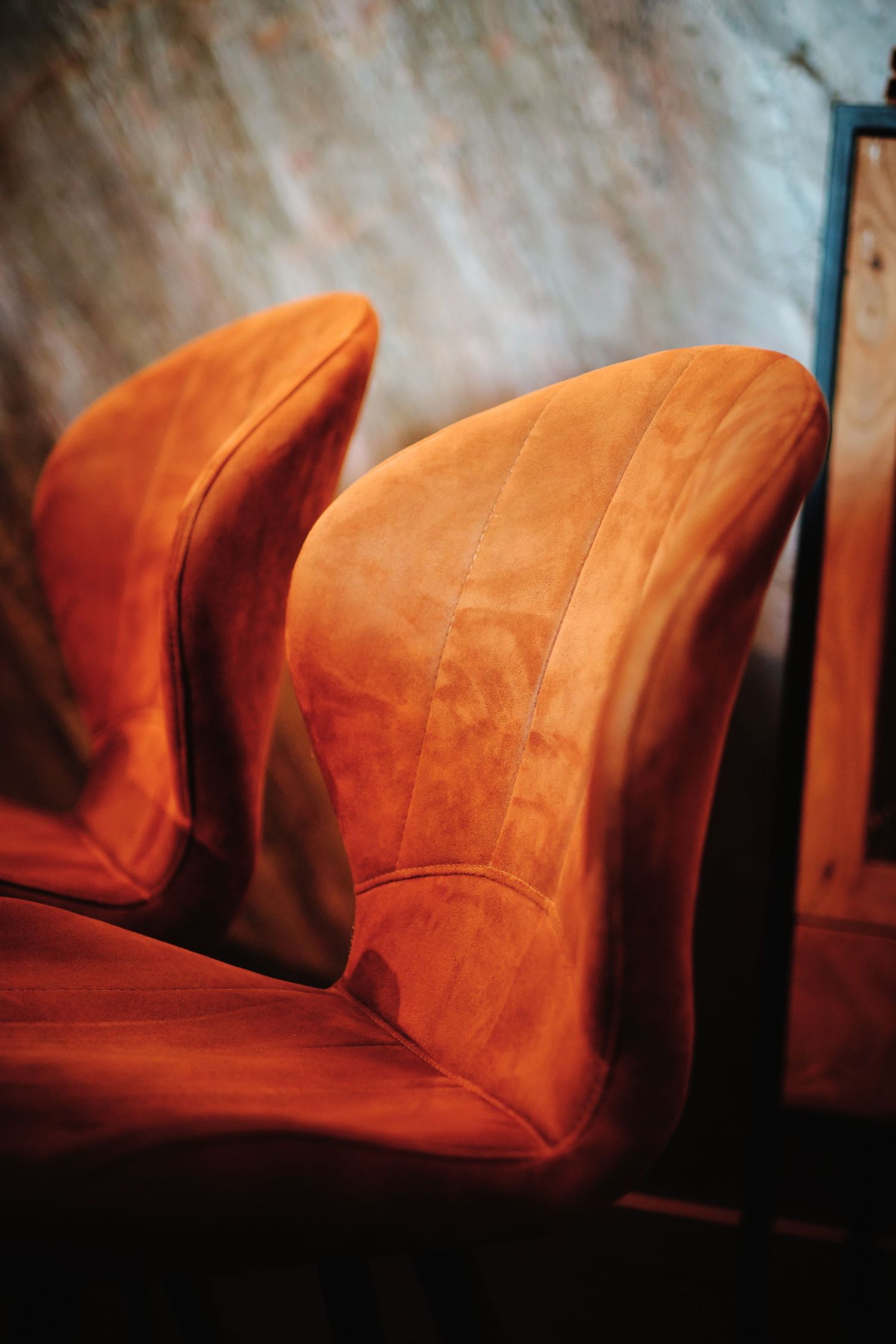 Row of plush orange velvet dining chairs in a restaurant setting with moody lighting.