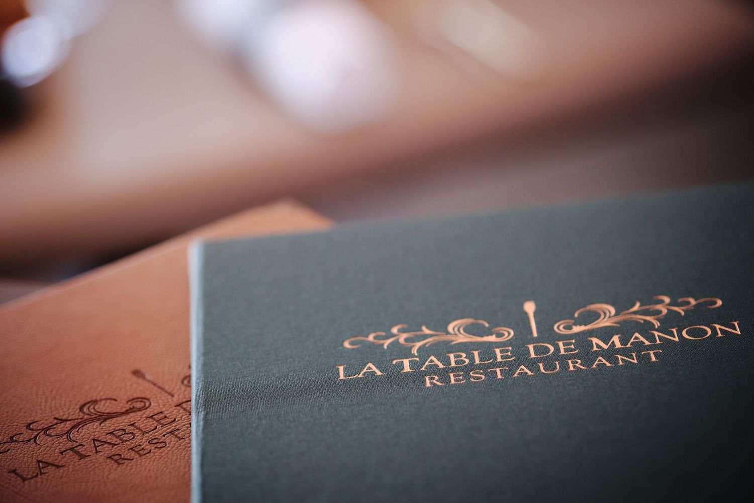 Close-up of elegant restaurant menu covers with gold lettering and ornate designs.