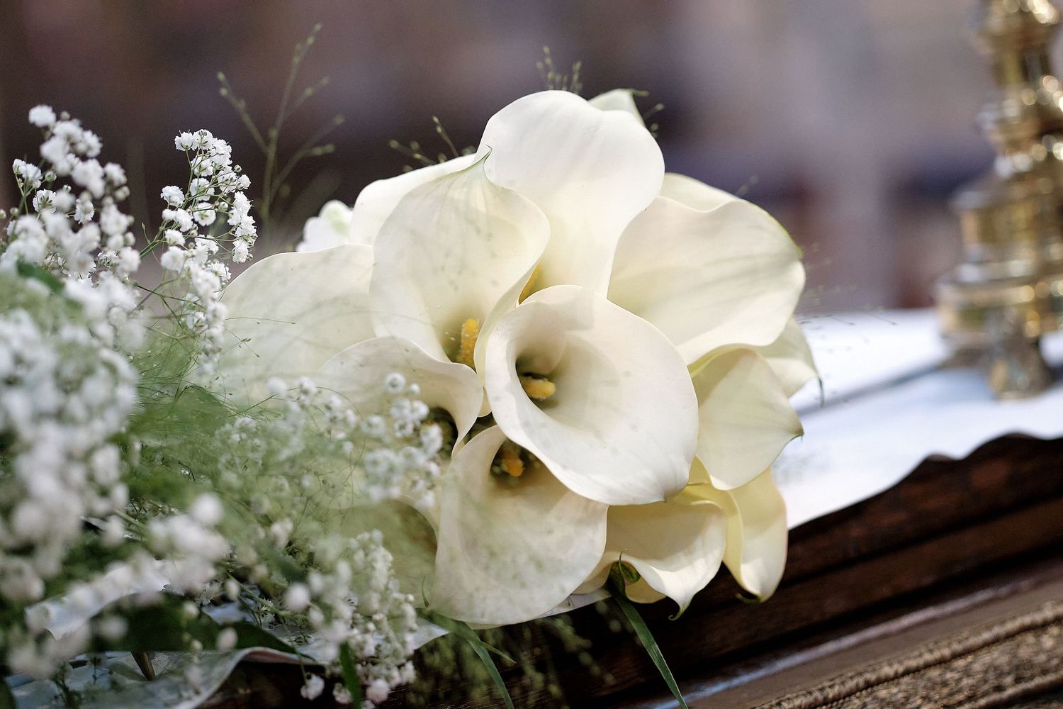 White calla lilies and baby's breath bouquet arranged on a decorative surface, perfect for weddings or elegant events.