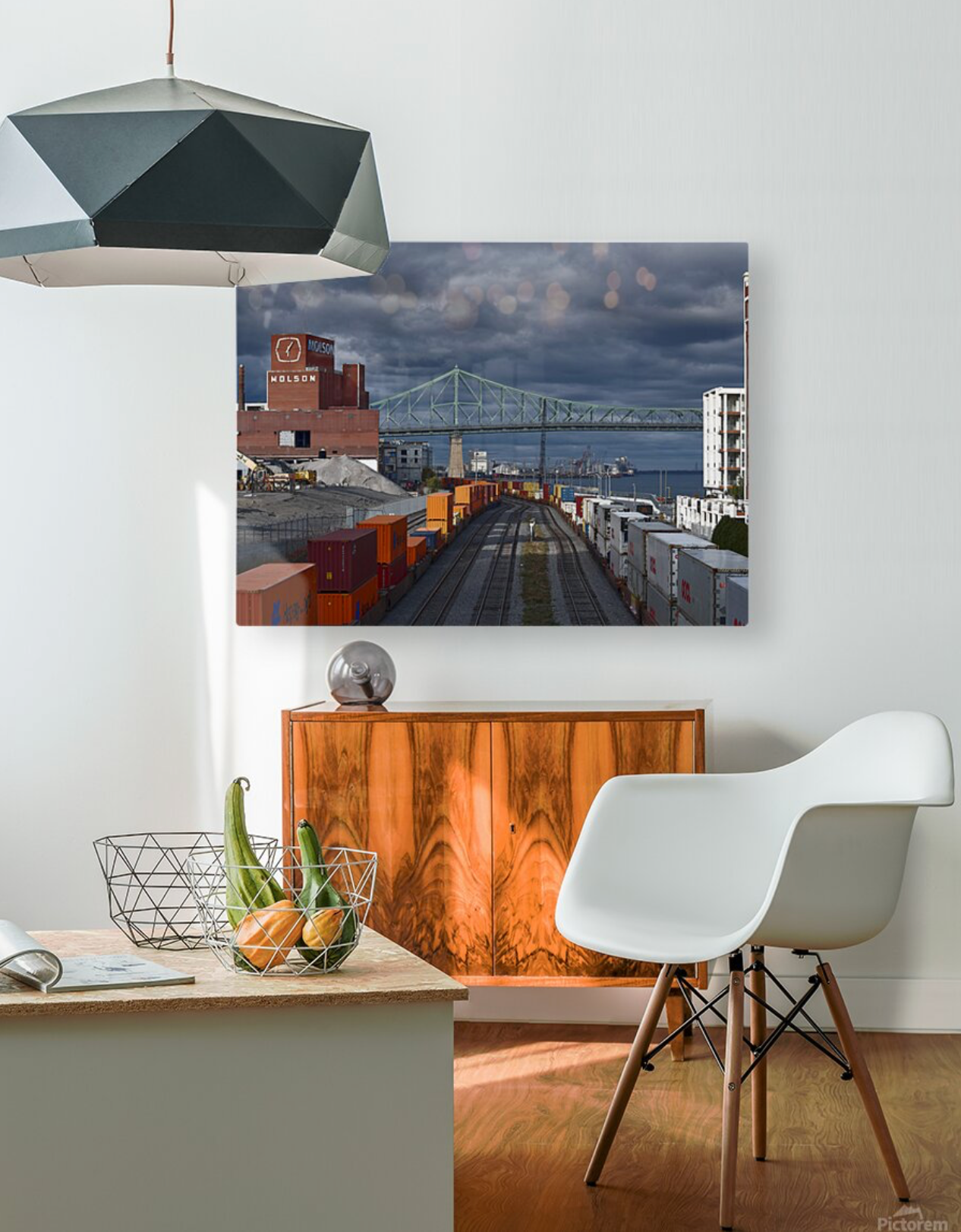 Modern interior design space with geometric pendant lamp, white chair, and urban bridge artwork displayed on wall.