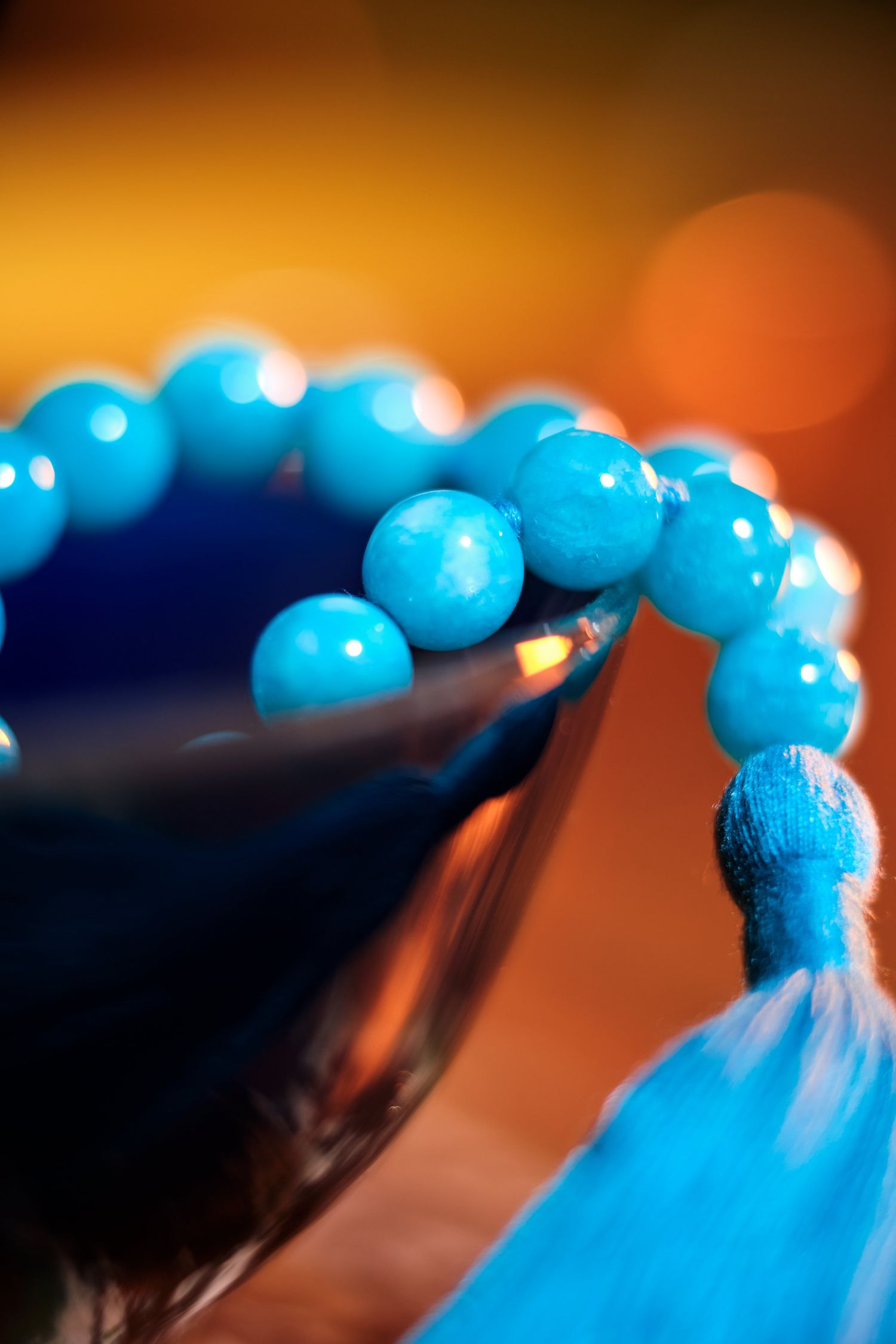 String of bright blue beads photographed against an orange background with shallow depth of field.