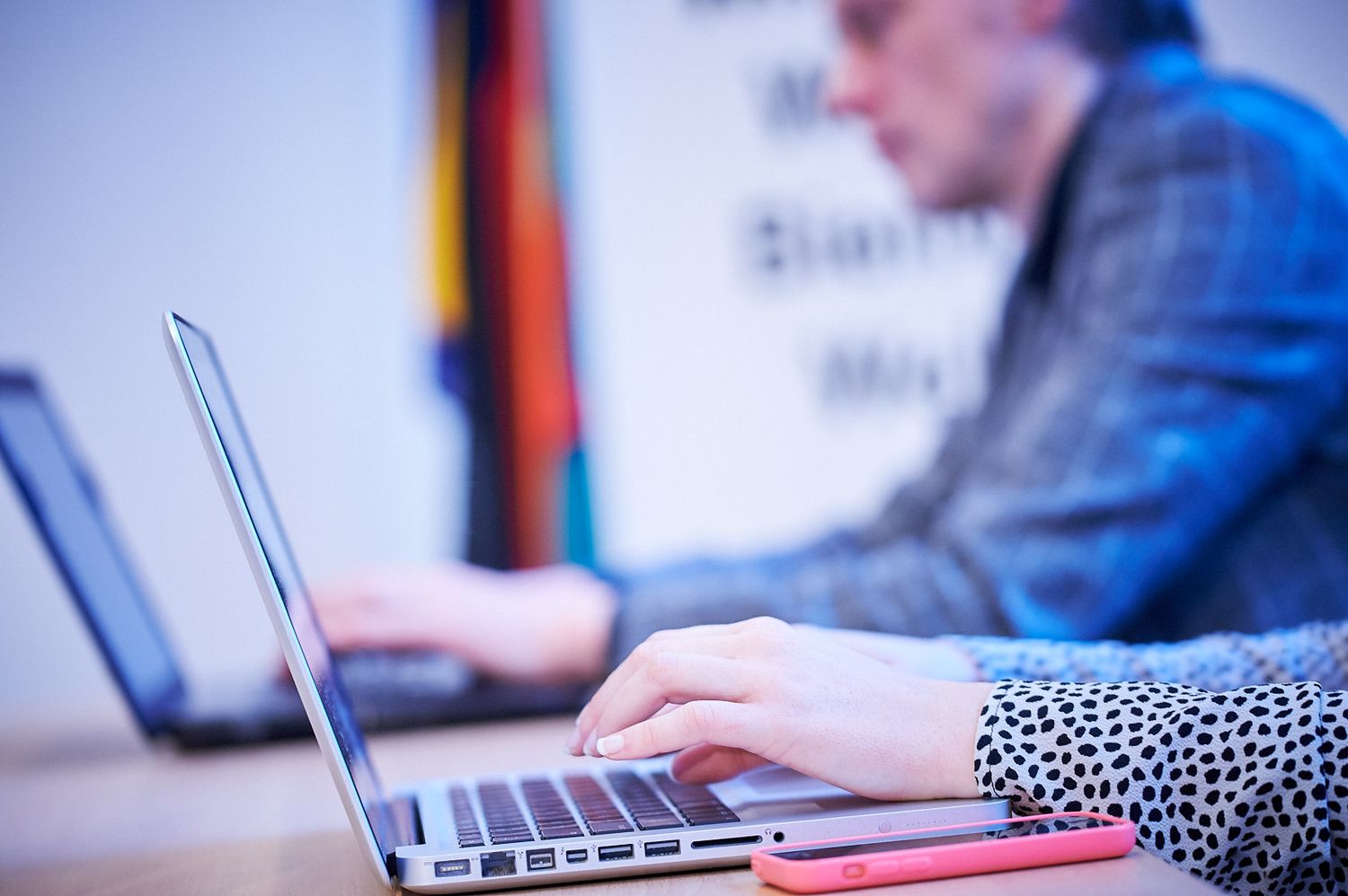 People working on laptops in a professional office setting.