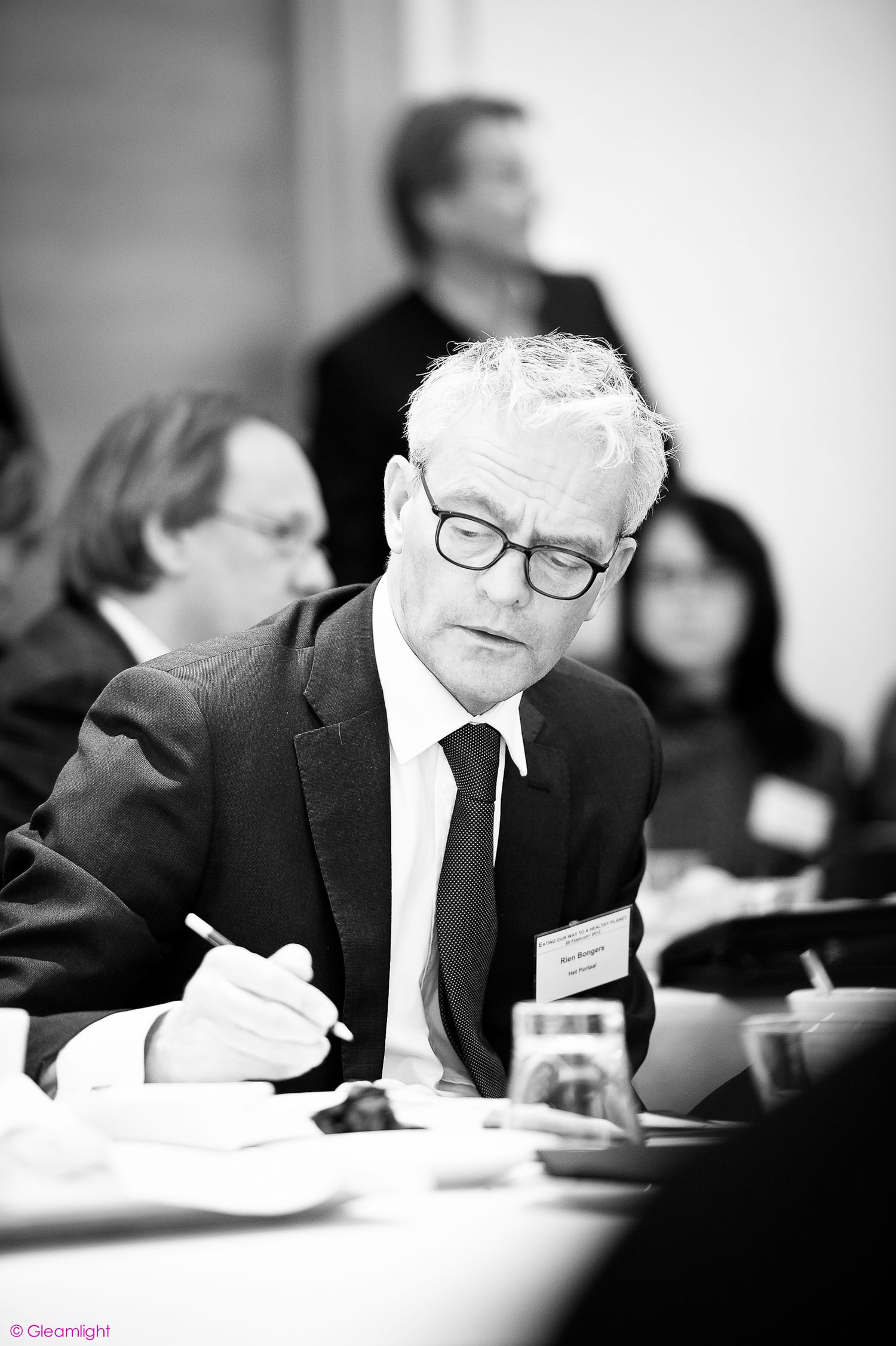 Black and white image of attendee taking notes during business meeting.