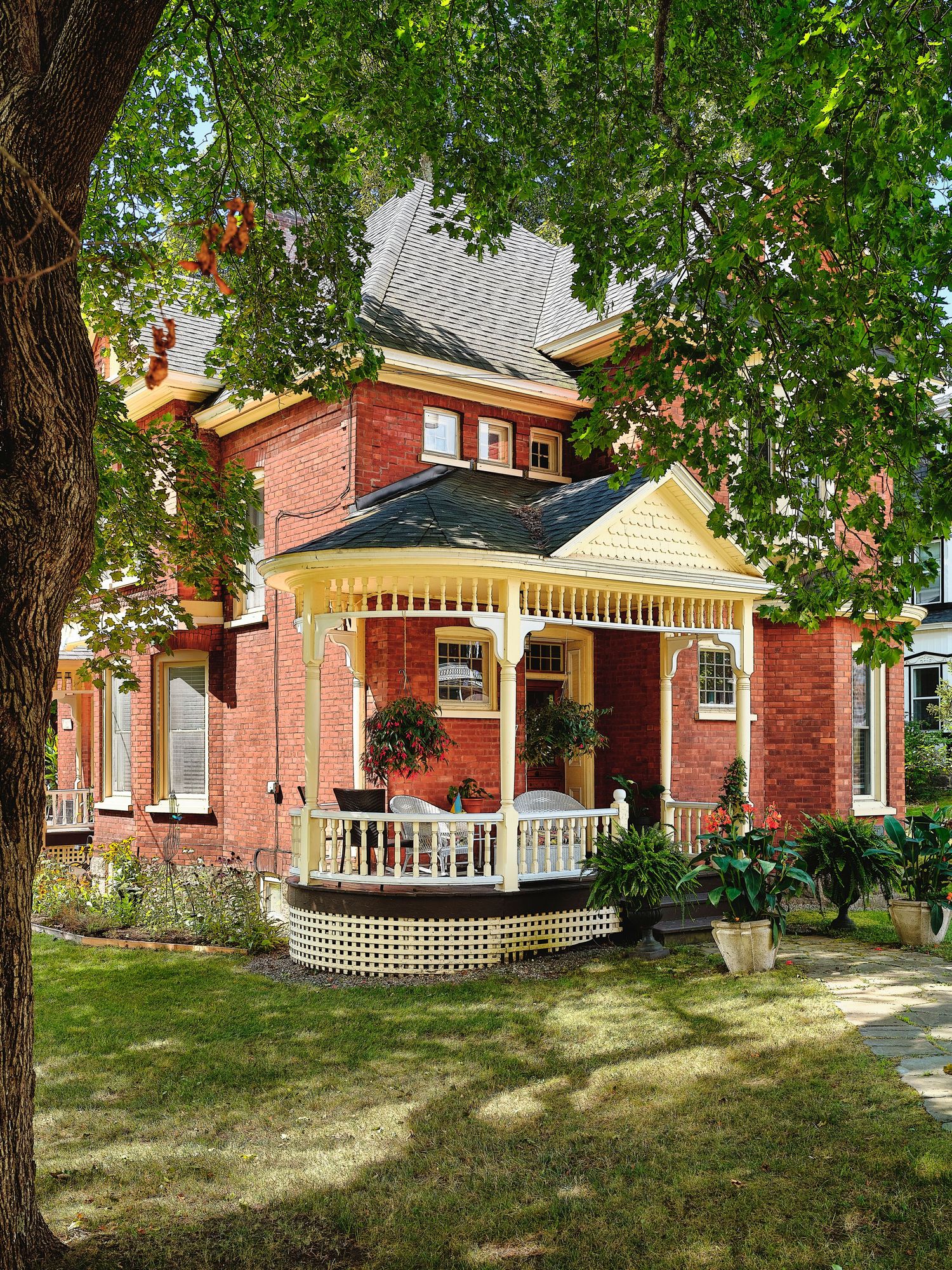 Row of historic red brick houses with white porches and trim along a tree-lined street.