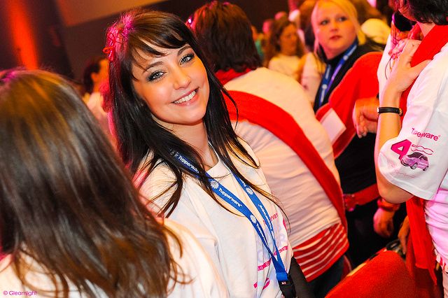 Crowd of conference attendees networking at an evening event with red ambient lighting.