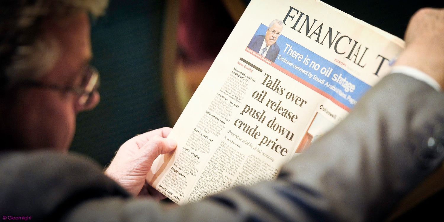 Attendee reading a financial newspaper during a business meeting.