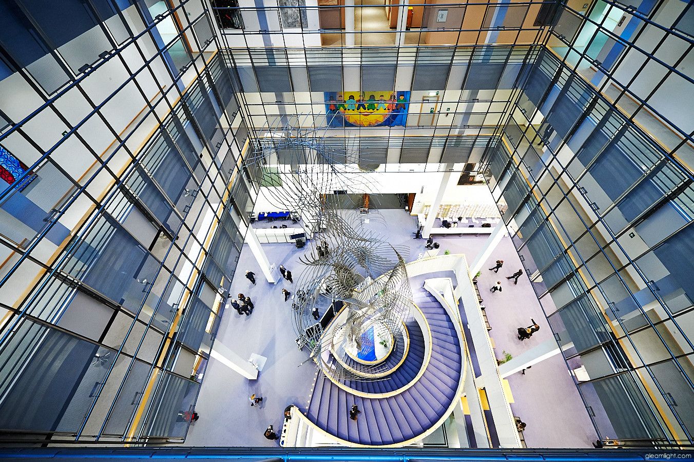 Modern office building interior with spiral staircase and glass architecture.
