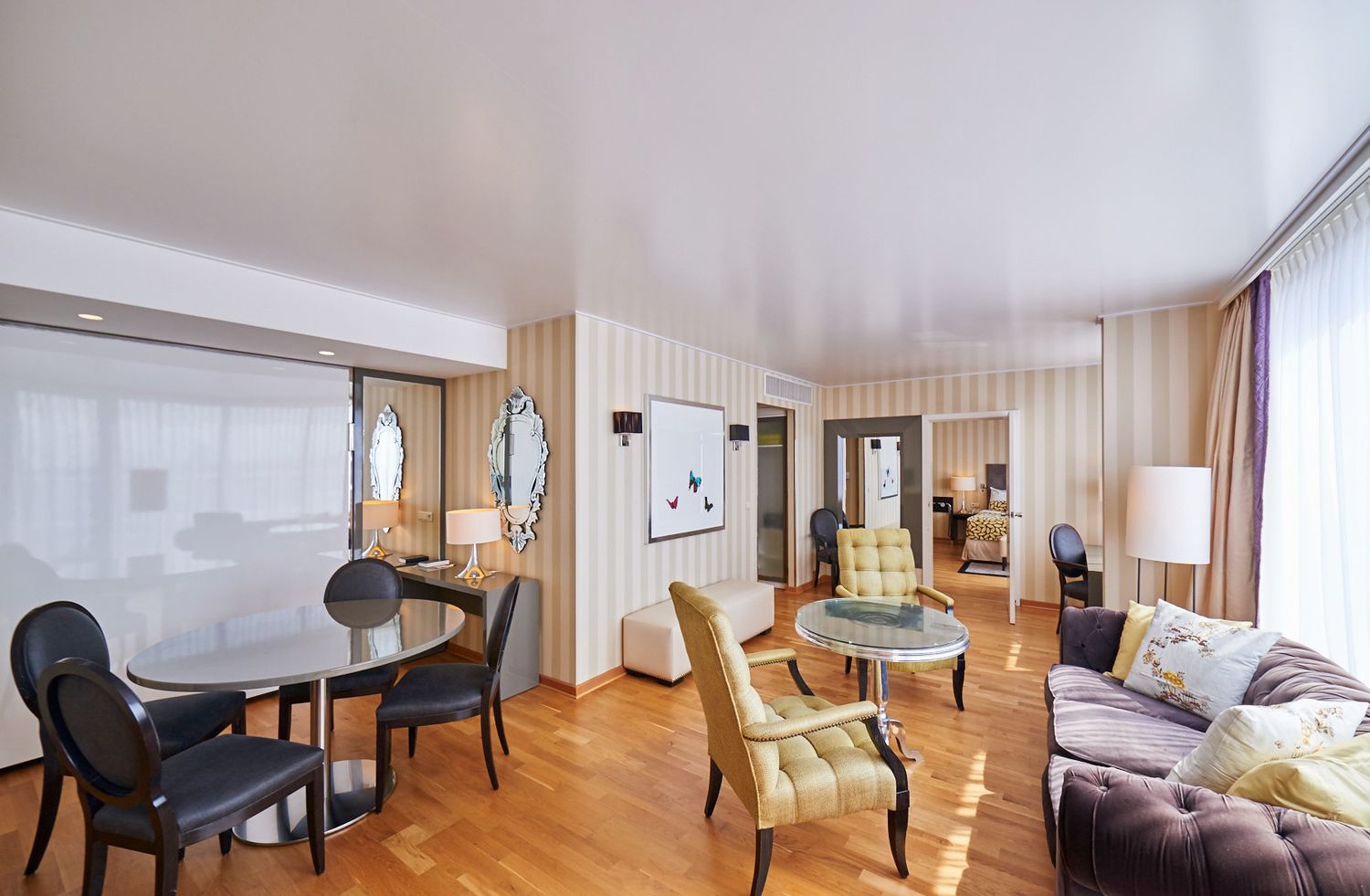 Modern hotel room interior with elegant furnishings and large windows providing natural light.
