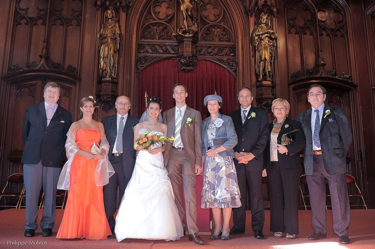 Wedding party posing together inside an ornate church, bride in white gown with family and guests in formal attire.