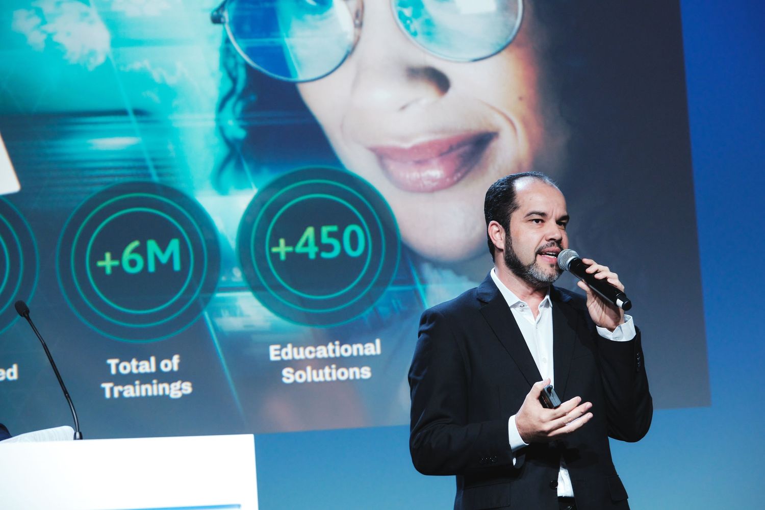Corporate presentation with blue digital display showing business metrics.