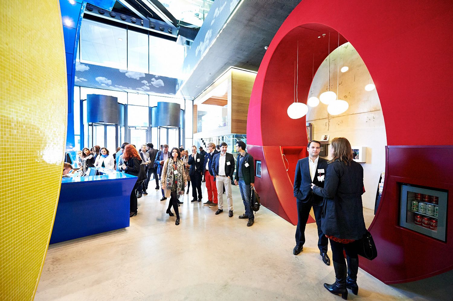 Modern office hallway with vibrant yellow and red walls and curved architectural features.
