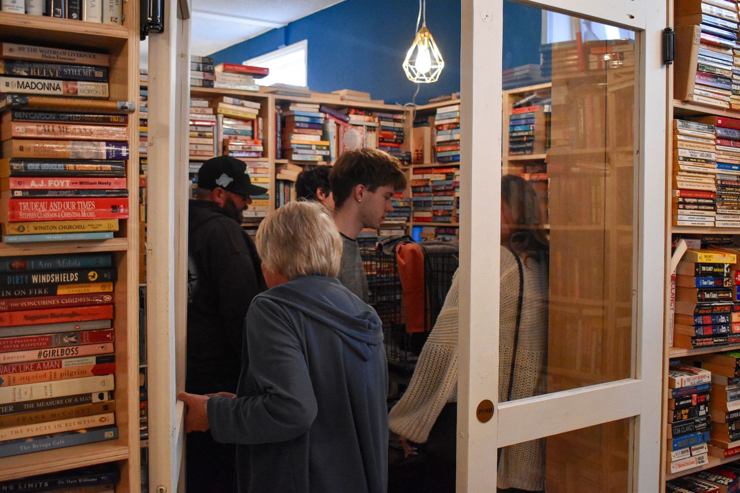 A cozy bookstore interior with wooden shelves filled with colorful books and pendant lighting fixtures.