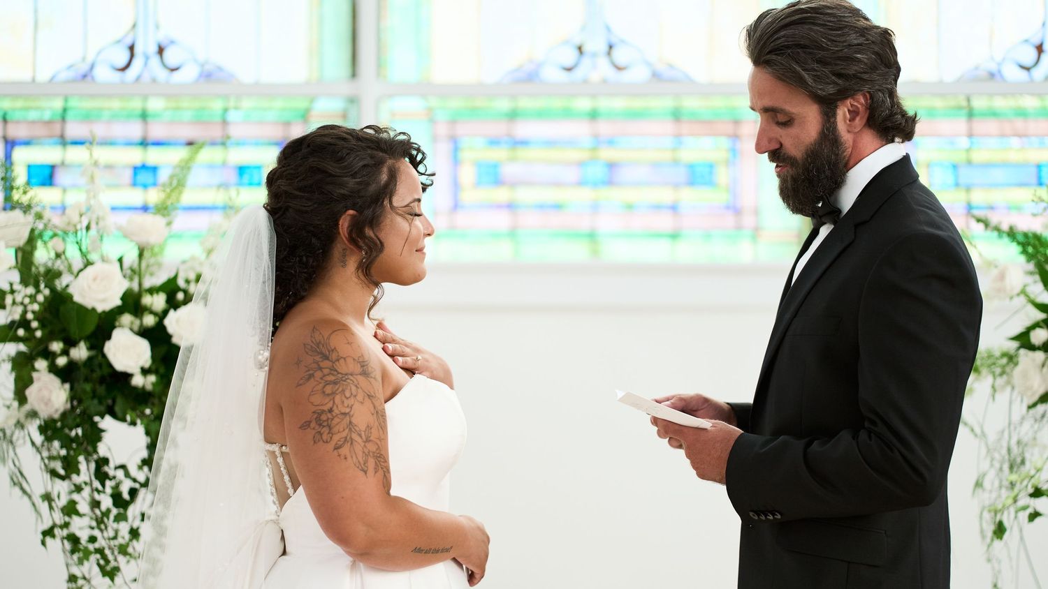 First look wedding moment captured in bright venue with stained glass windows.