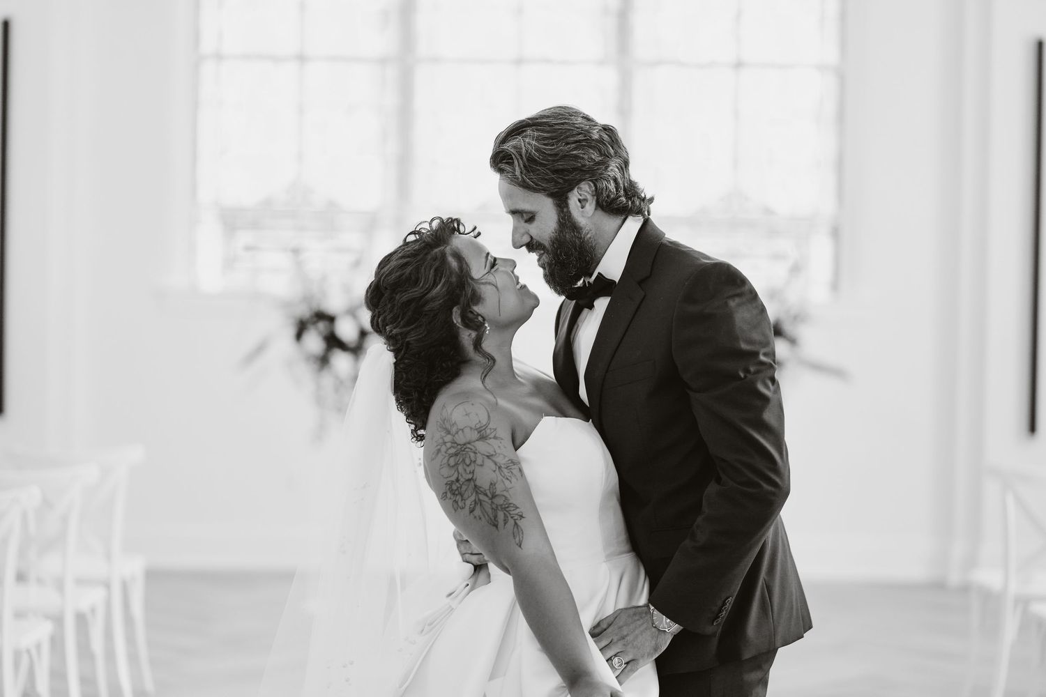 A black and white photo captures an emotional wedding ceremony moment between two people.