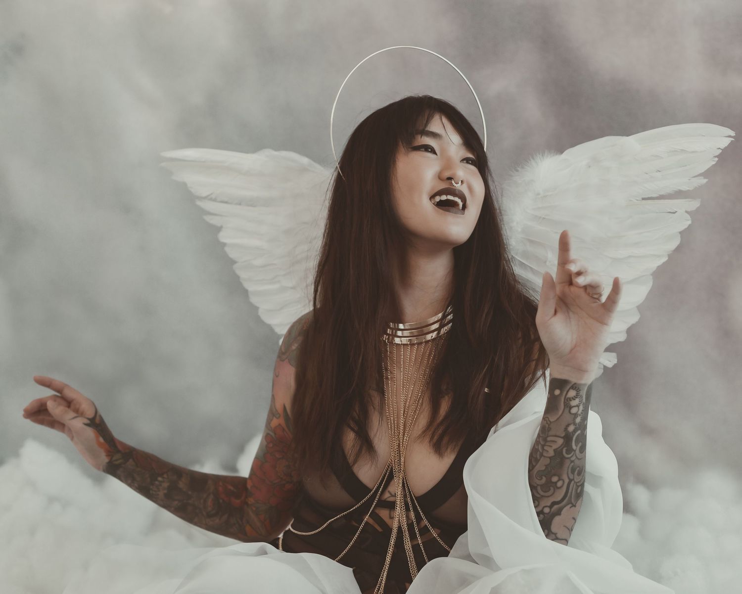 Expressive angel-themed boudoir portrait with gothic styling against cloudy backdrop.