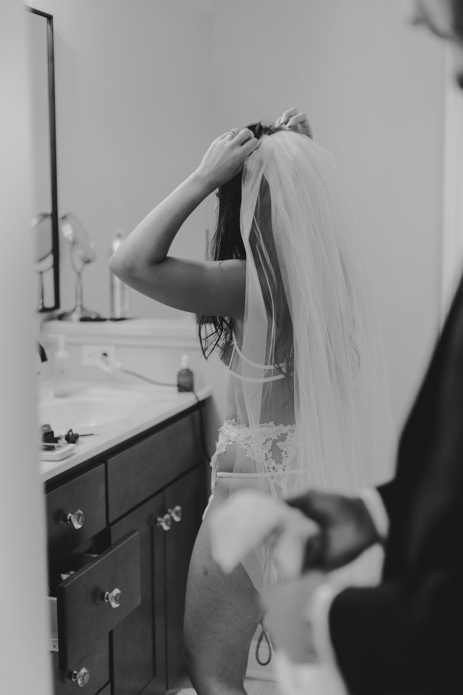 Black and white photo of preparation moment in bathroom with wedding veil.