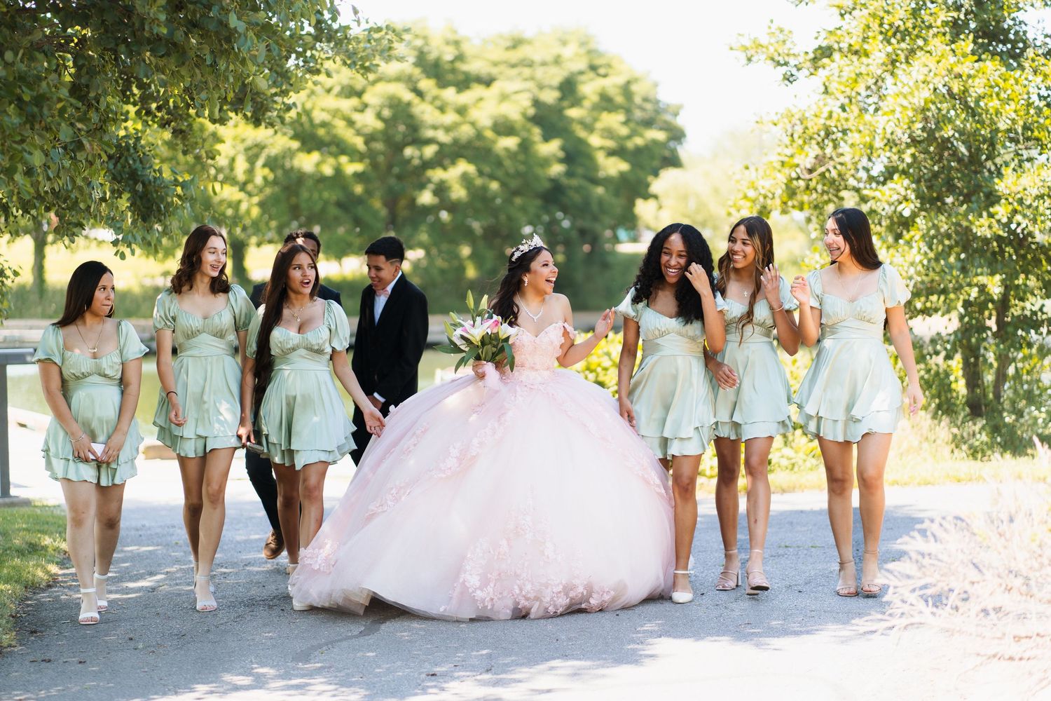 Bridesmaids in mint green dresses pose with the bride in a garden setting.