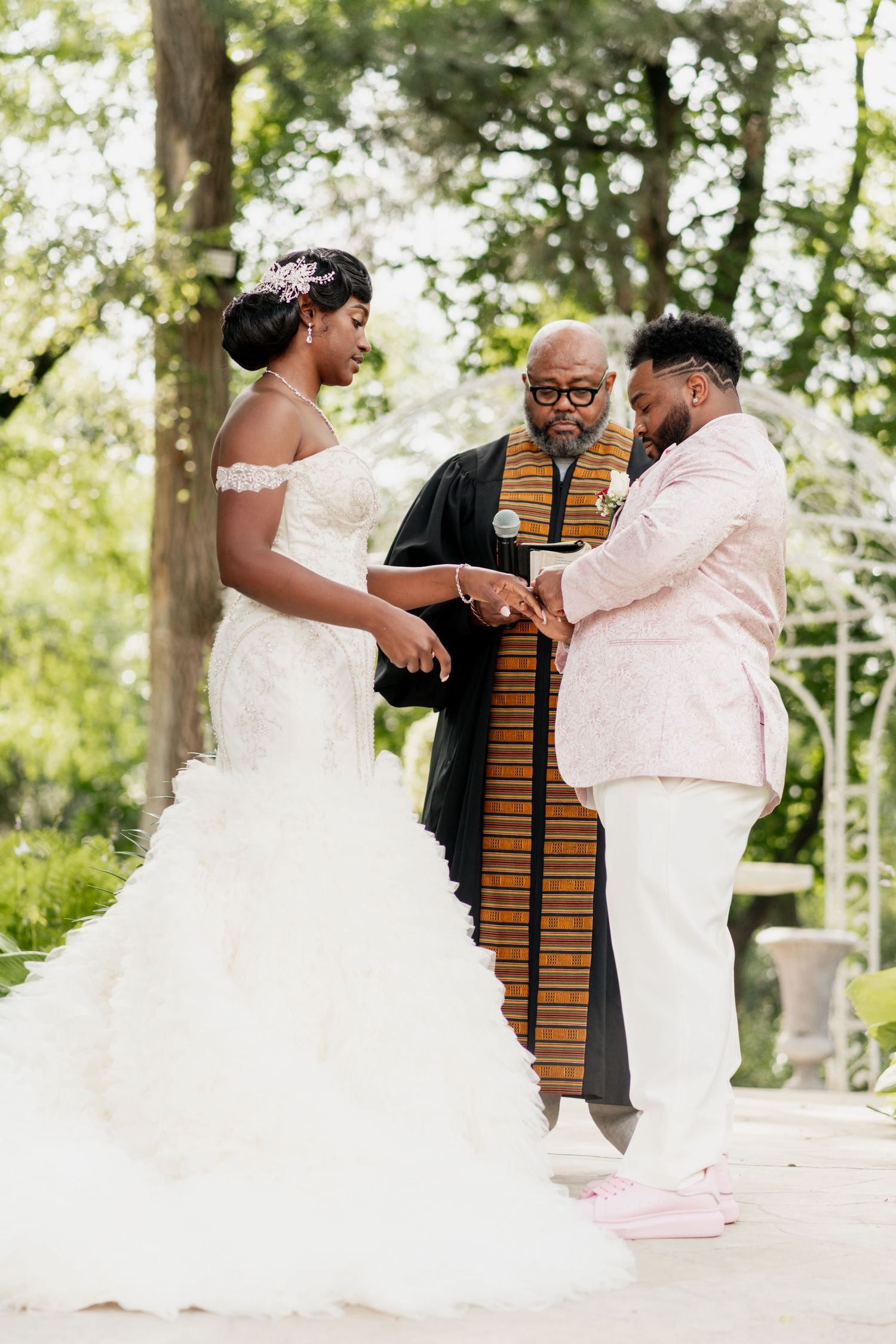 Wedding ceremony at white gazebo with couple exchanging vows.