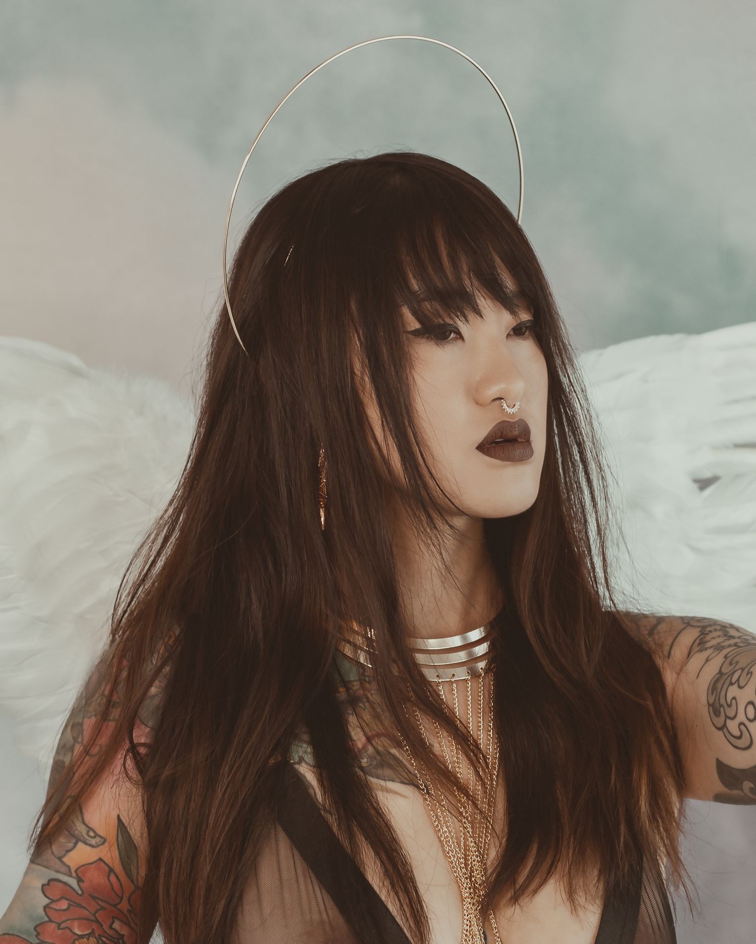 Close-up portrait with halo effect featuring dark lipstick and long hair against cloudy backdrop.