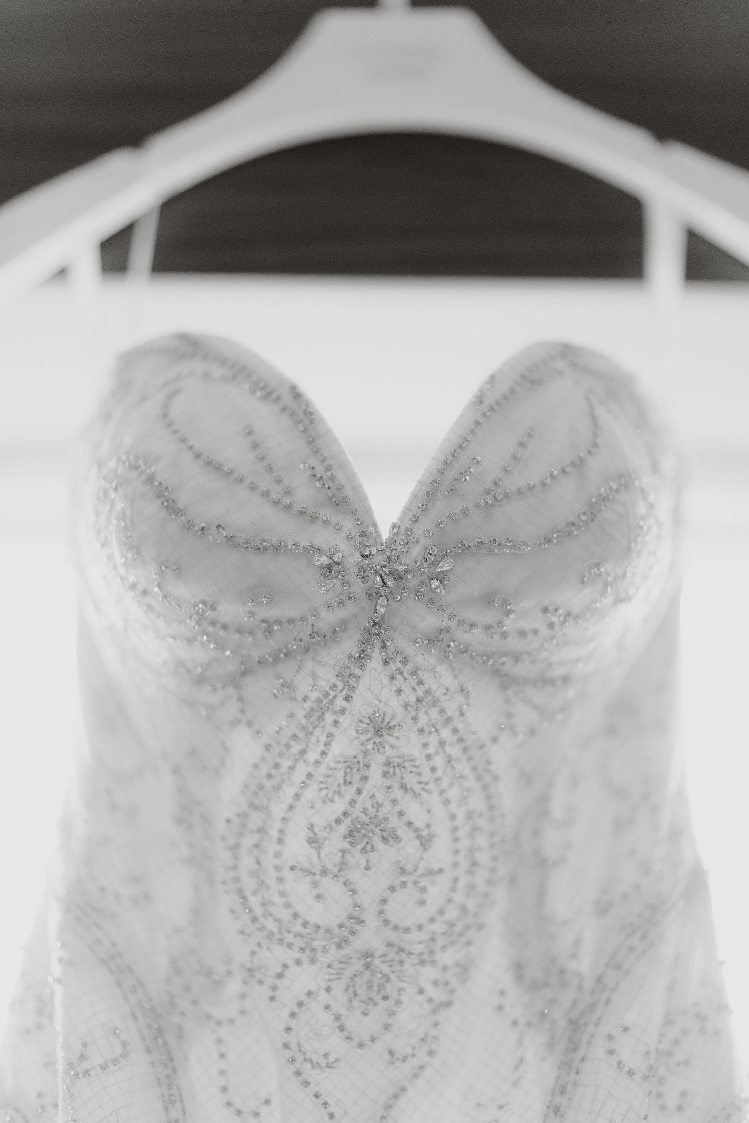 Close-up detail of a wedding dress bodice showing intricate beaded pattern and sweetheart neckline.