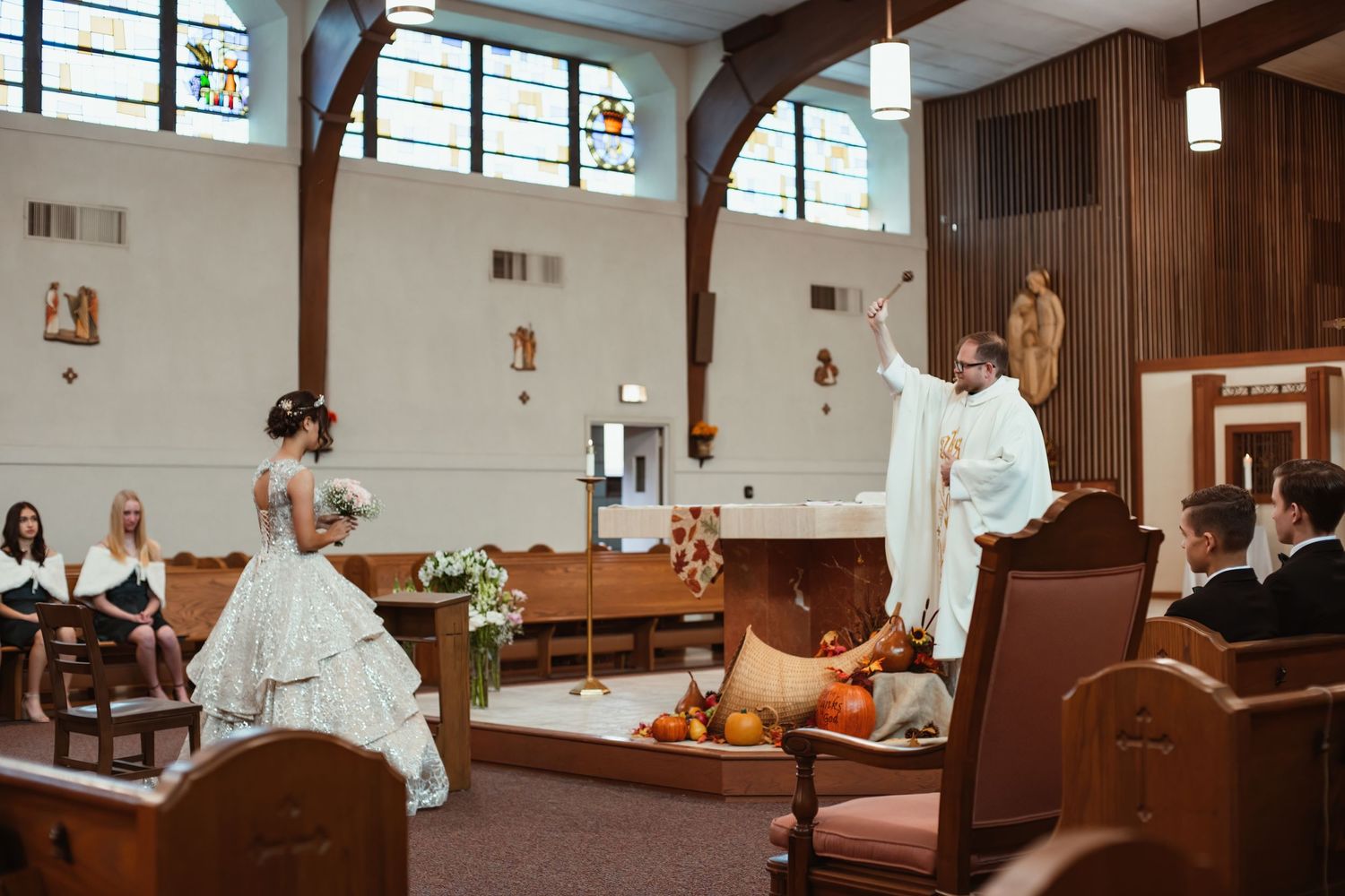 A wedding ceremony in progress inside a church sanctuary with wooden beams and pendant lights.