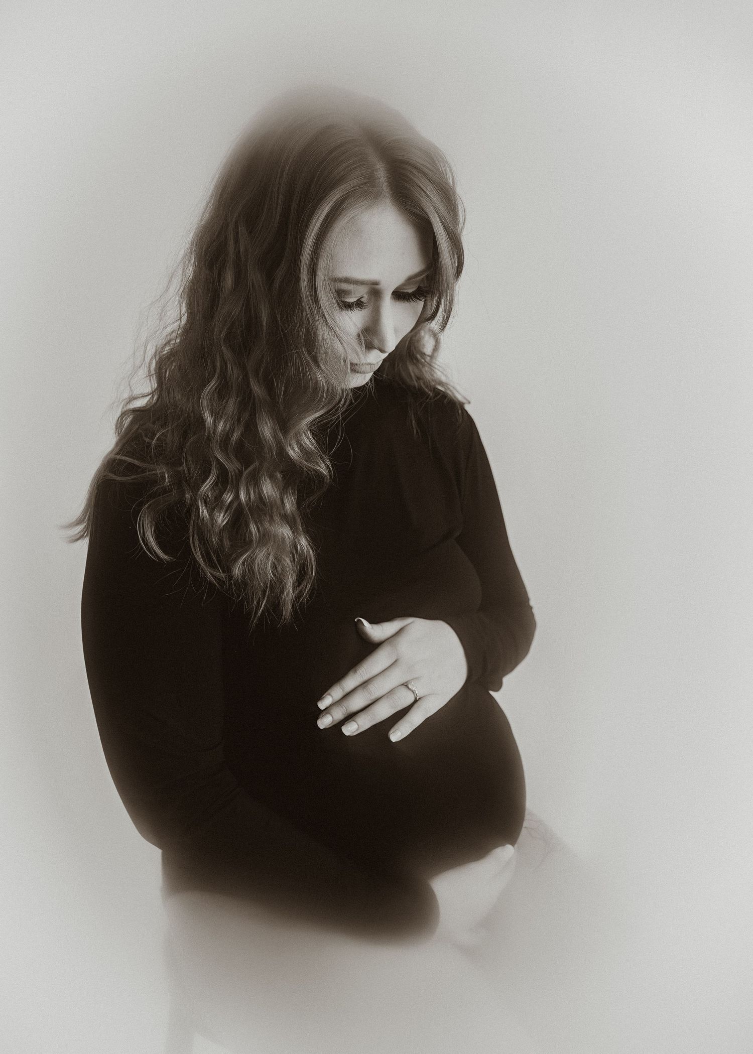 Intimate black and white maternity portrait showing gentle moment of reflection.