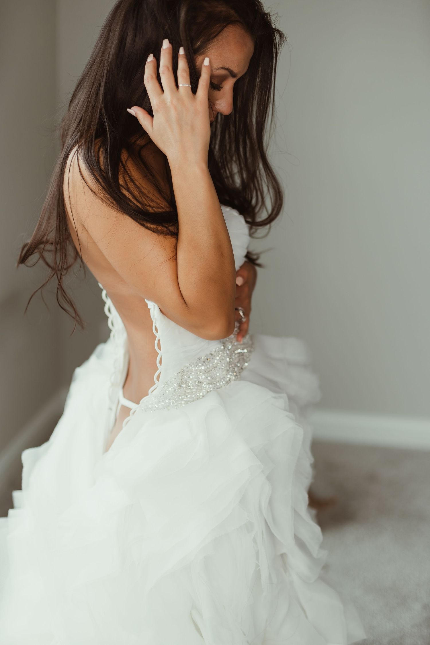 White wedding dress with lace detail and ruffled tulle skirt photographed from behind.