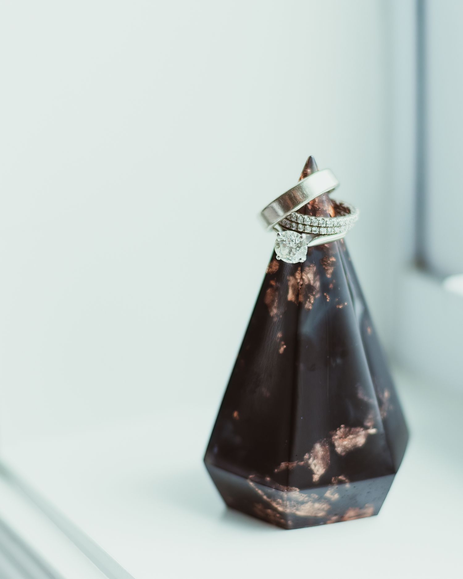 A dark geometric vase or decorative object with a ring placed on top.
