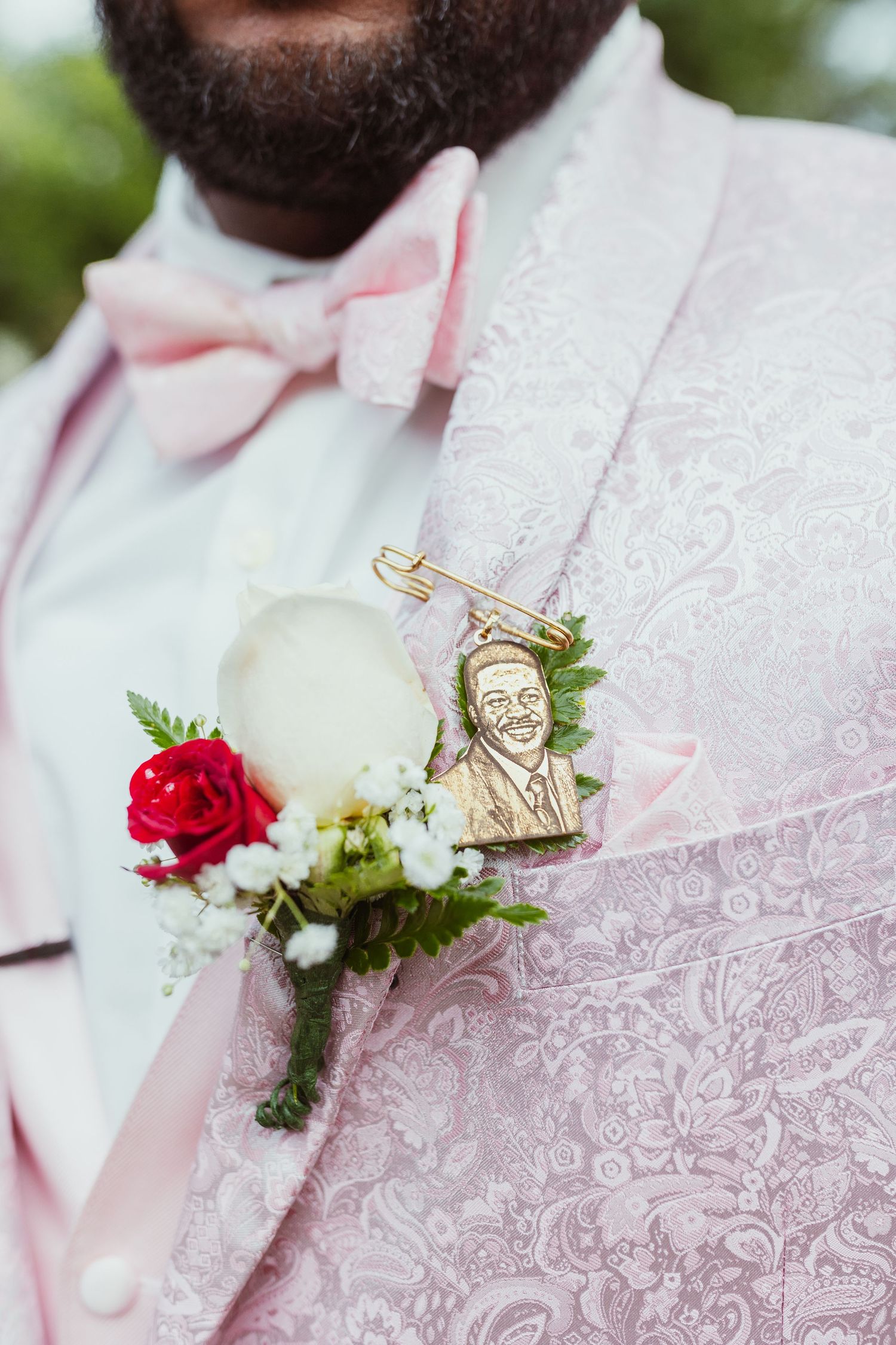 Pink brocade suit jacket with red rose boutonniere and decorative gold pin.