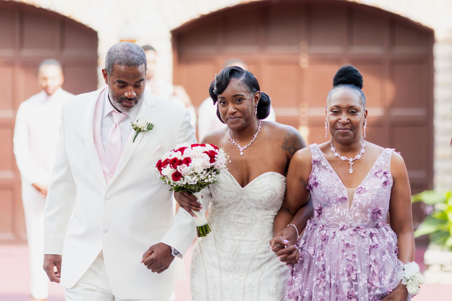 Wedding party members pose together during outdoor ceremony at brick venue.