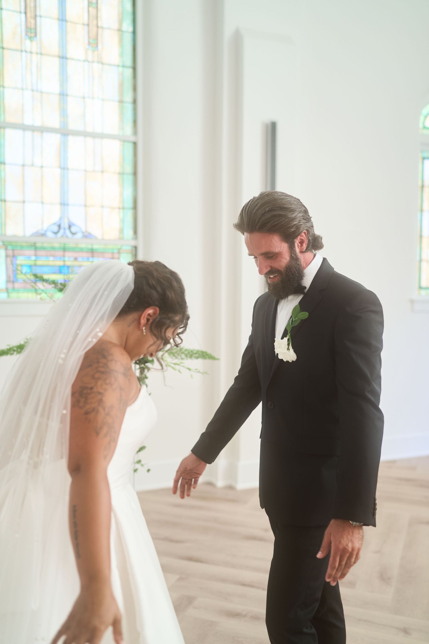 A joyful wedding moment captured in a bright chapel with stained glass windows and hardwood floors.