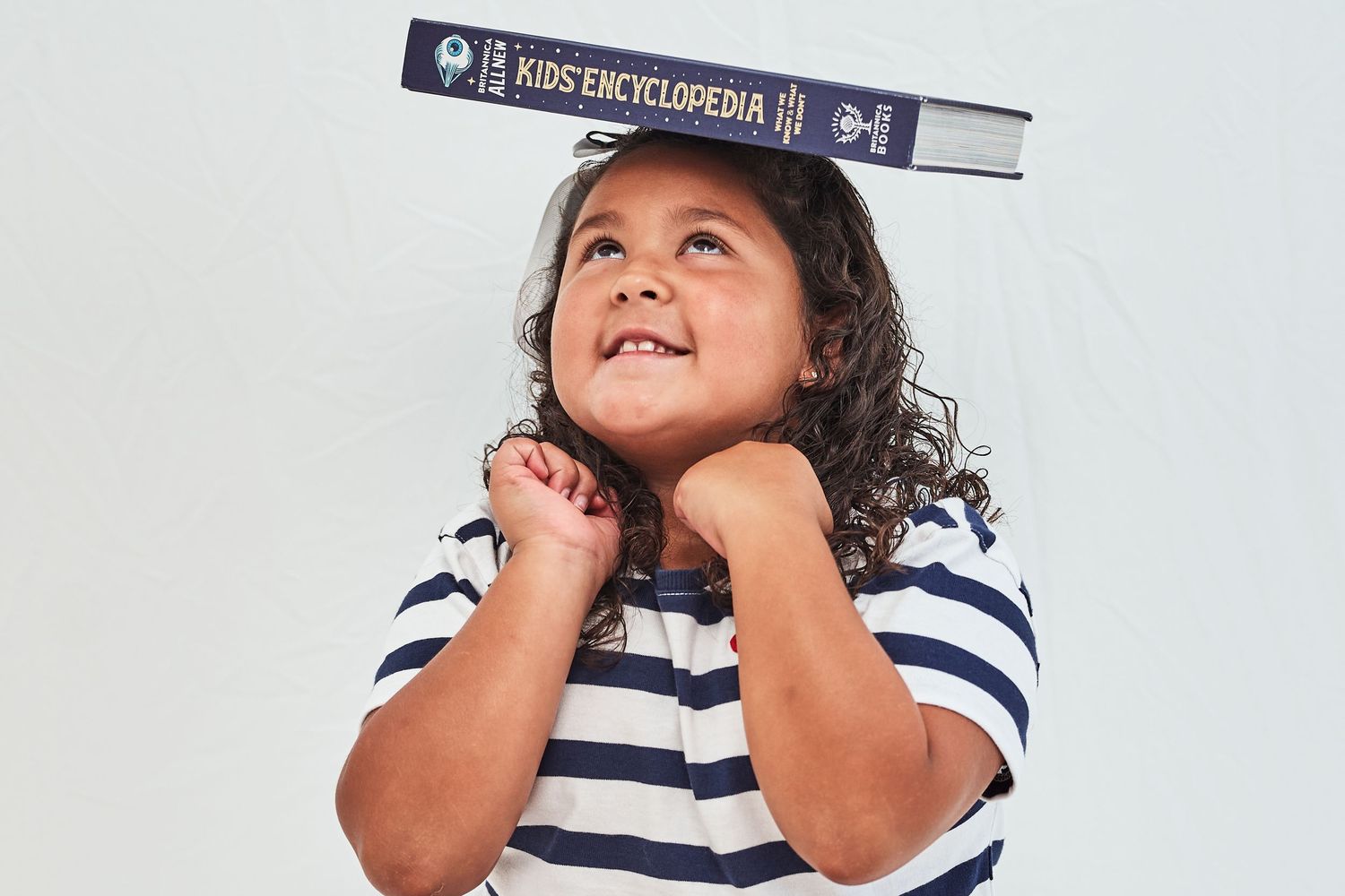 A young child in a striped shirt plays and makes silly faces while looking upward in this photo collage.
