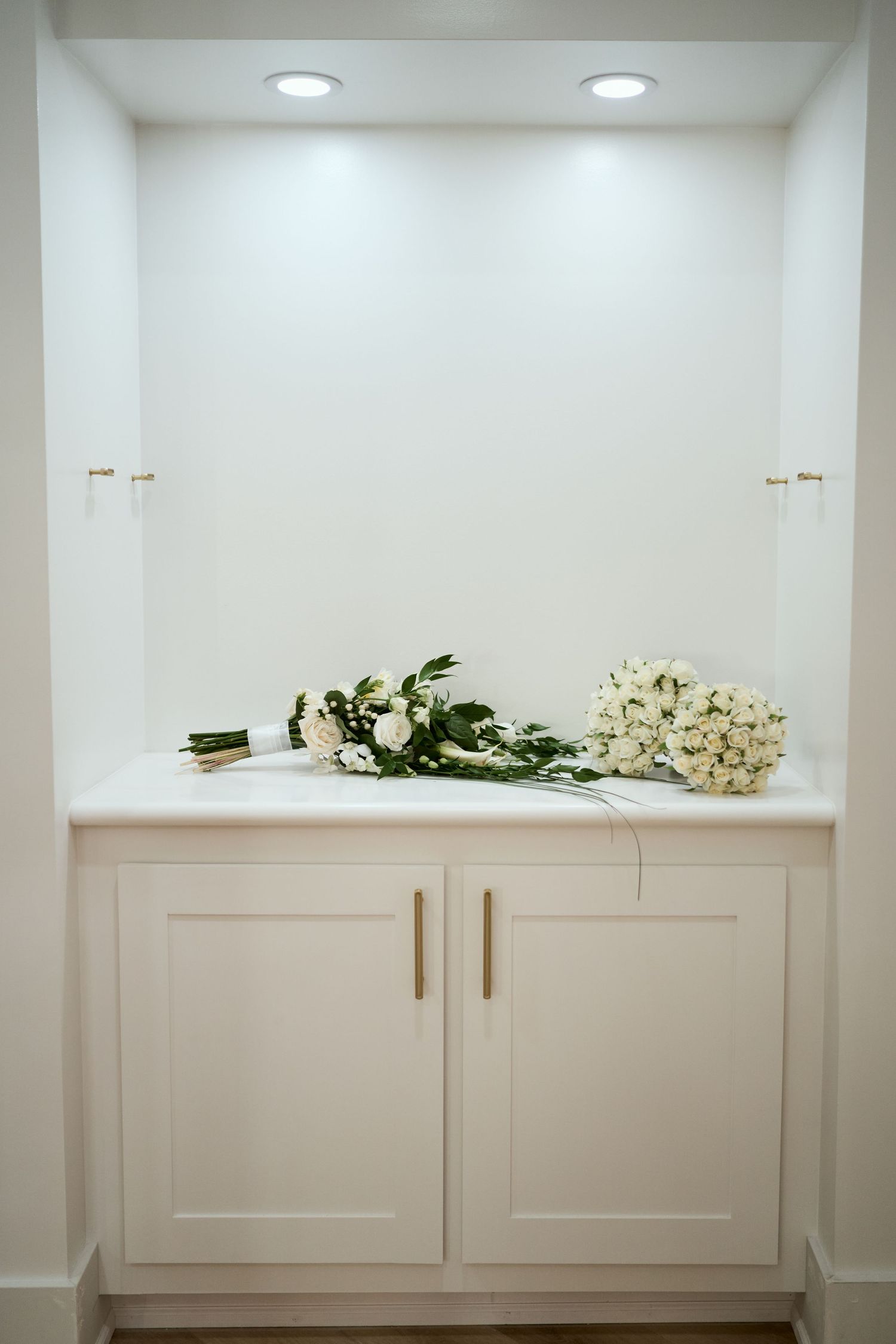 A white floral bouquet rests on a built-in cabinet shelf with recessed lighting.