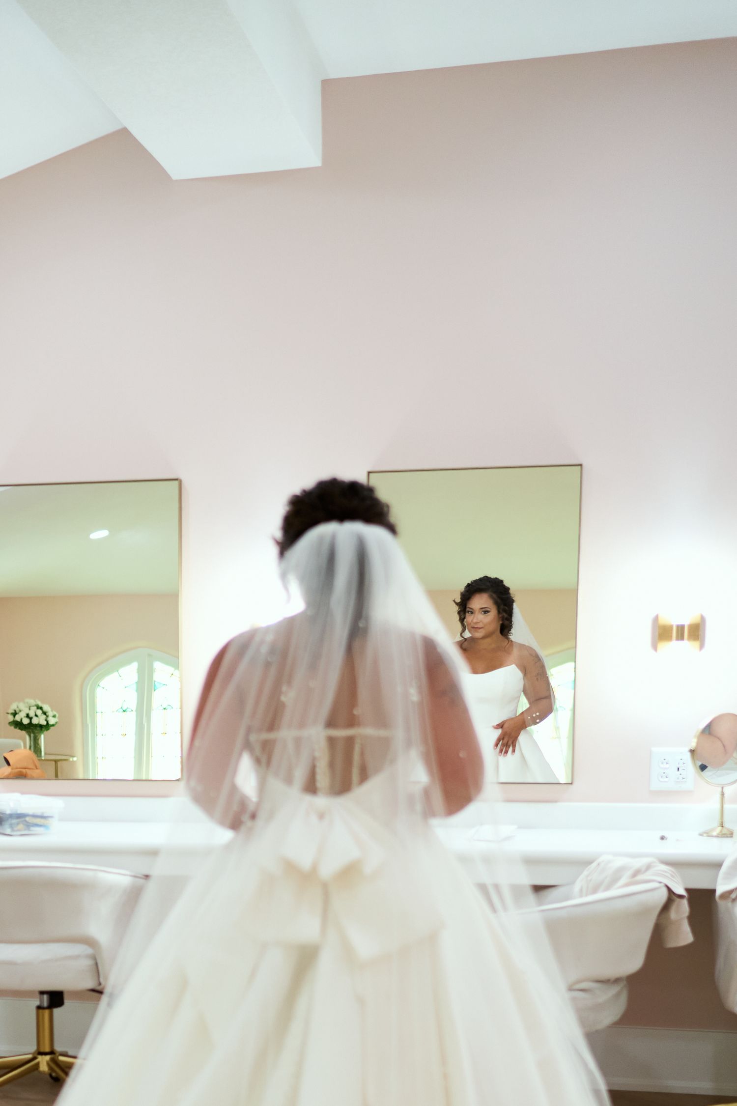A dreamy bridal scene with flowing white wedding dress and veil in natural light.