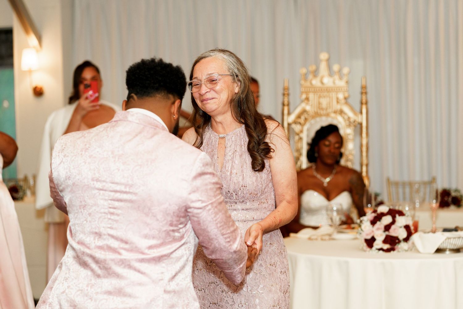 Wedding reception dance floor moment with guests celebrating in pink and white attire.