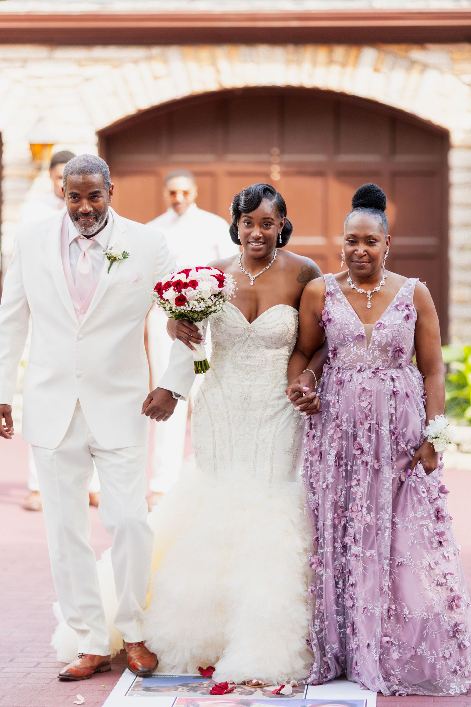 Wedding party poses together on a red brick walkway during ceremony.