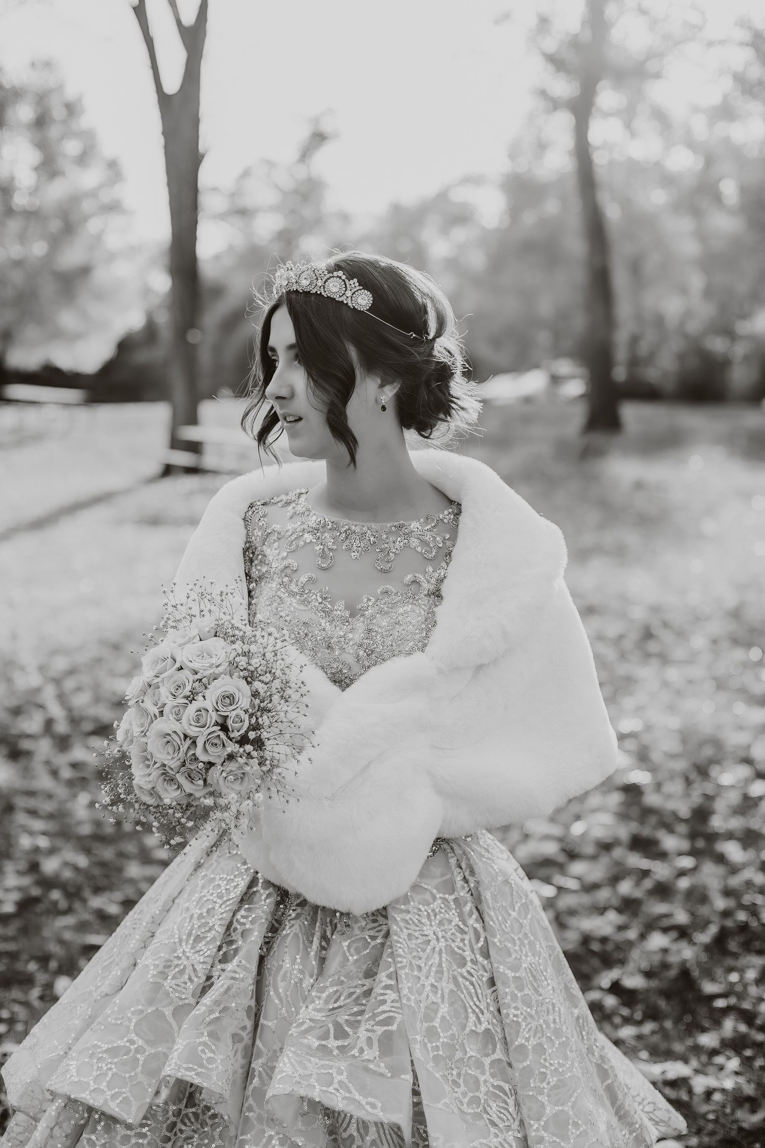 Black and white bridal portrait with fur wrap and lace gown in outdoor setting.