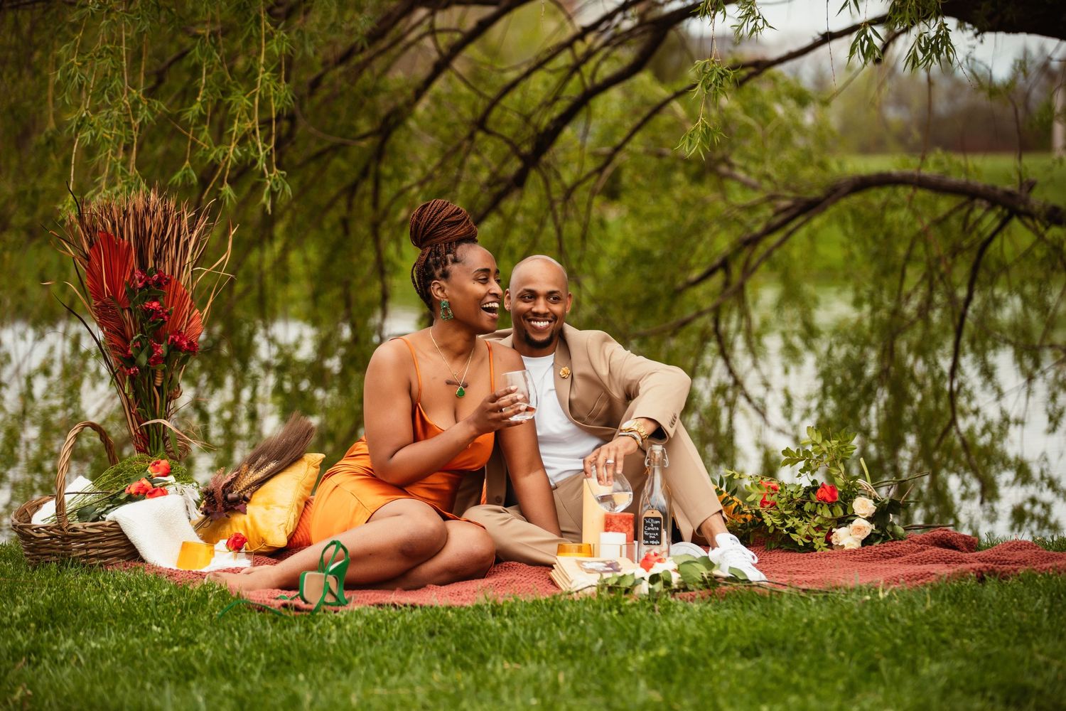 Romantic outdoor picnic scene with couple enjoying wine by a lake.