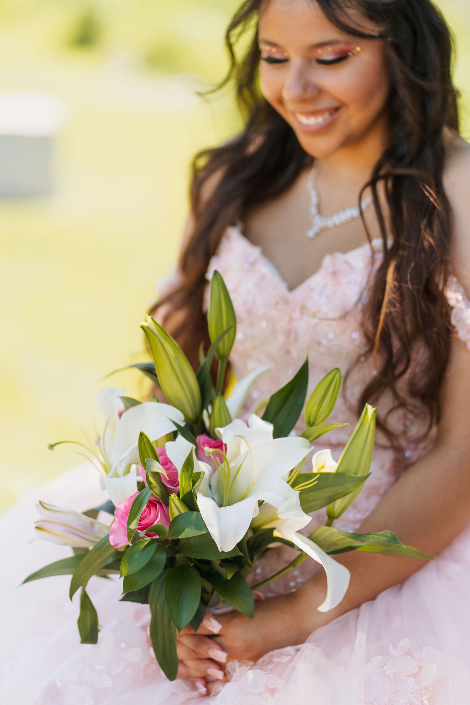 A bouquet of white lilies and pink flowers held against a pink formal dress.