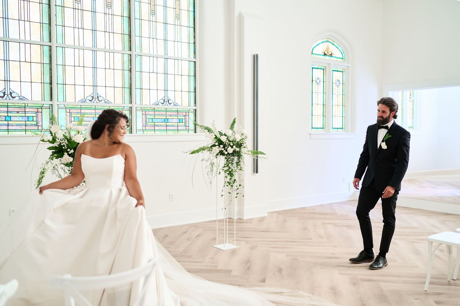 A bright modern wedding chapel with stained glass windows and white chairs lined in rows.