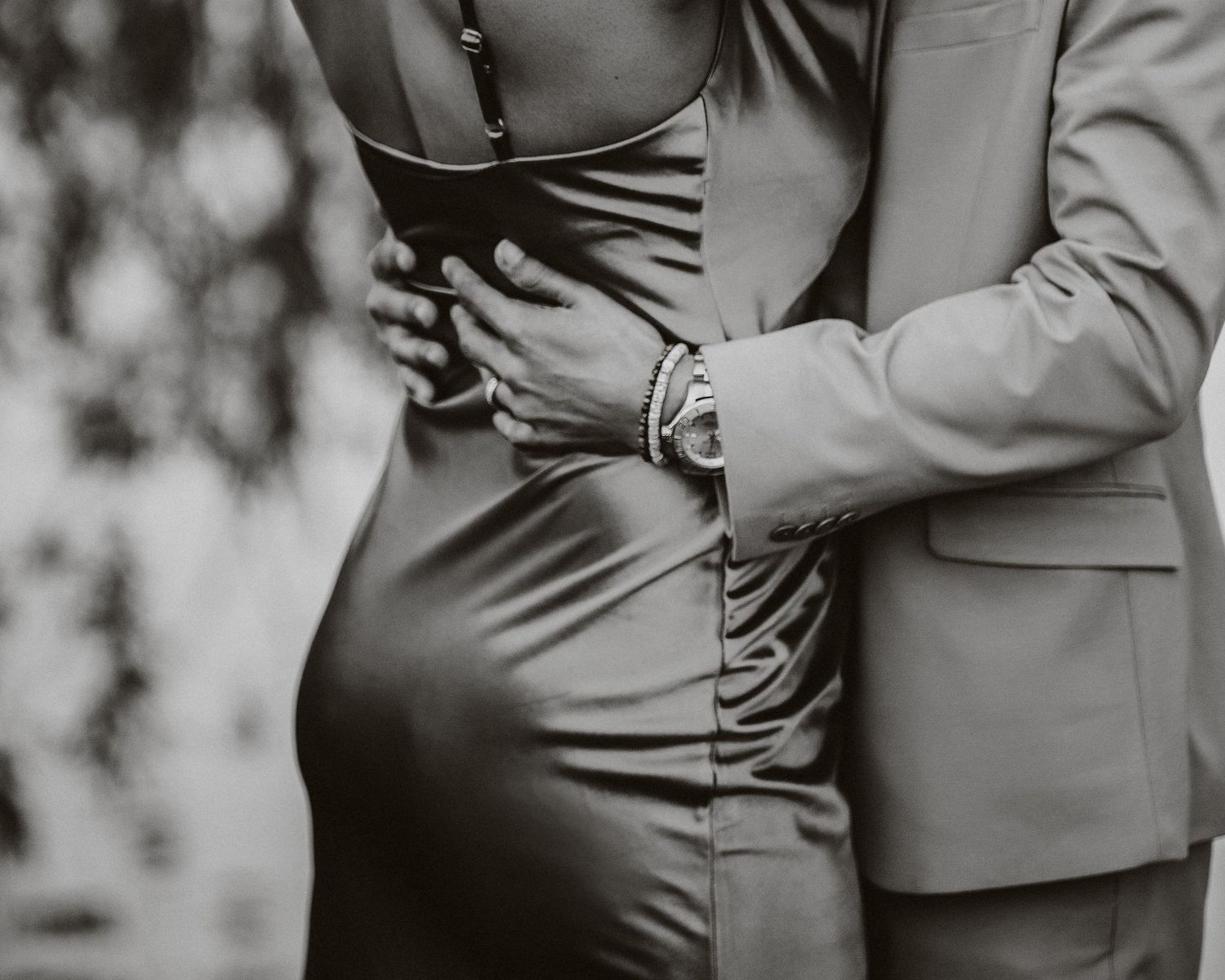 Black and white intimate embrace showing couple in formal attire with focus on midsection.