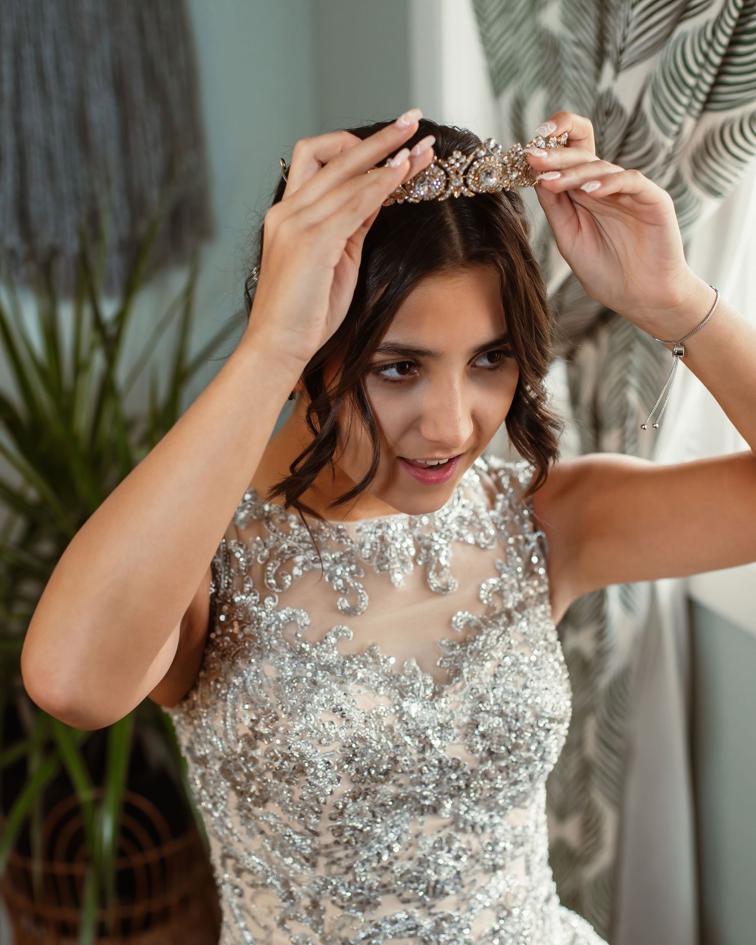 A delicate crystal tiara being placed atop an ornate wedding ensemble.