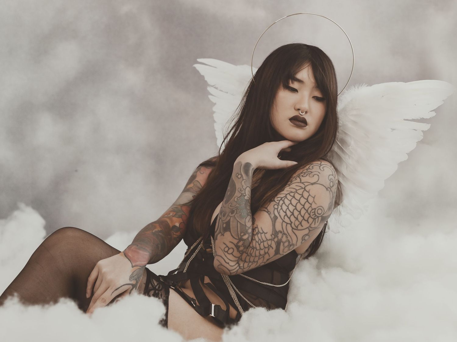 Gothic angel themed portrait with white wings against misty background.